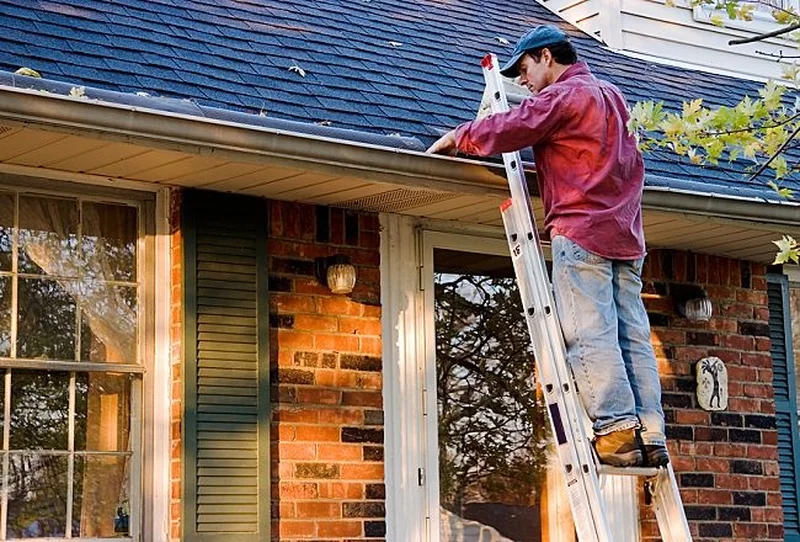 Technician on a ladder cleaning gutters on a Richmond, VA home